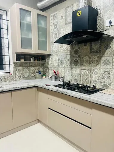 L-Shaped Kitchen with Patterned Backsplash & Black Chimney